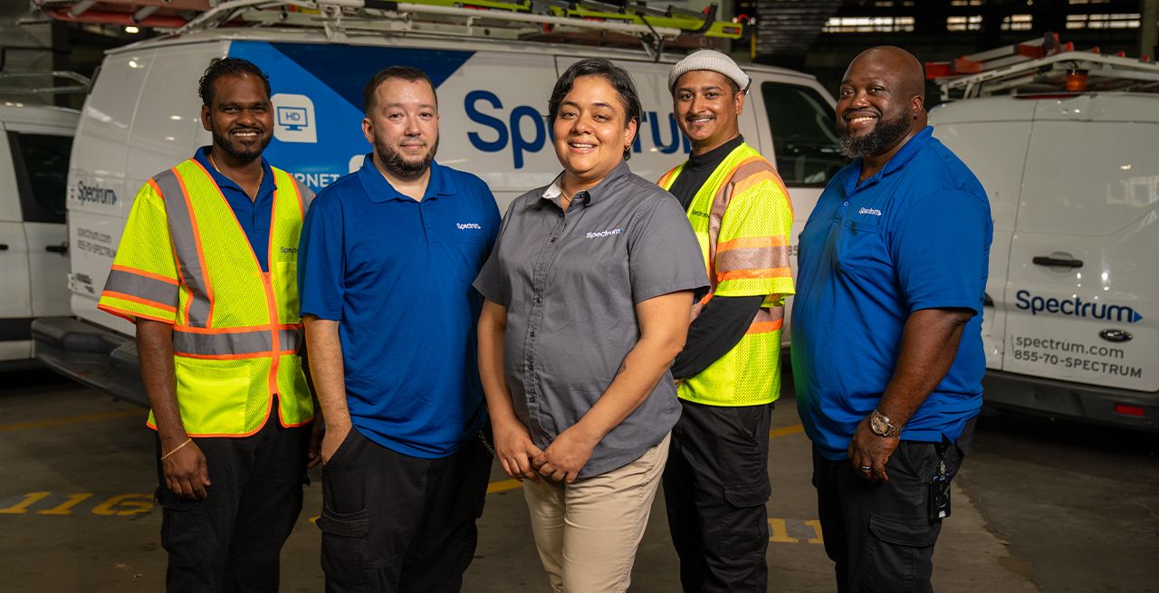 Diverse group of Charter co-workers posing in front of a Spectrum van