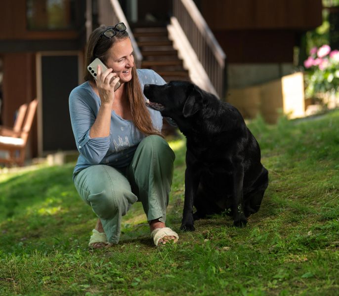 A woman using her smartphone while with her dog
