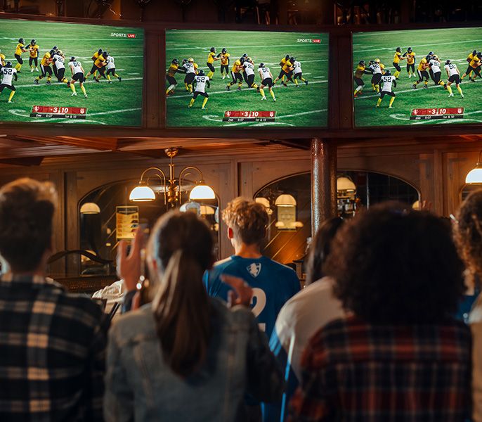 A crowd of people cheering at sports broadcasting in a bar 