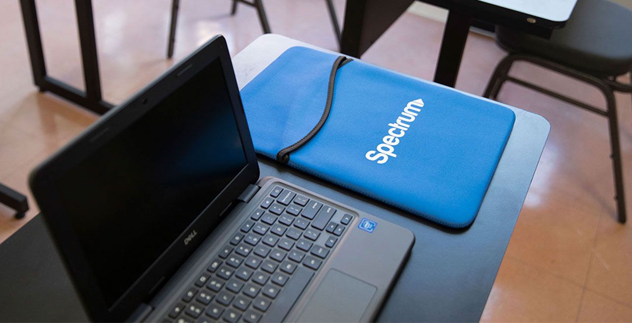 Laptop and mouse pad with Spectrum logo sitting in an empty computer lab