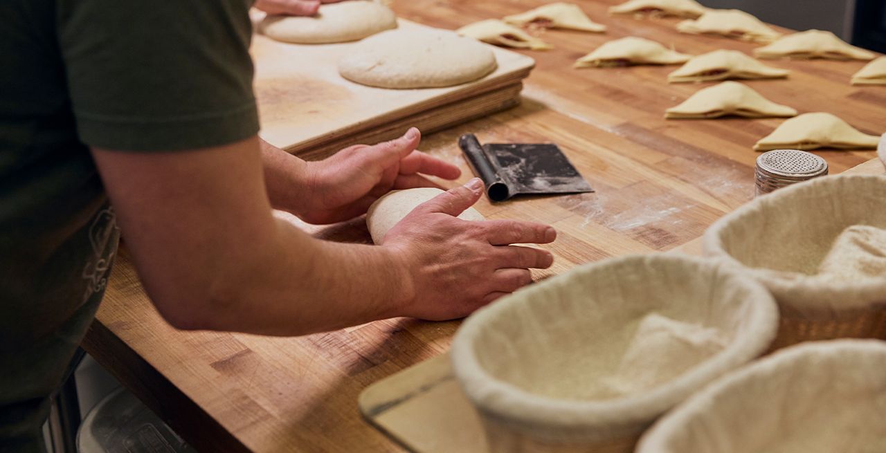A worker kneading dough at Rise Bakery