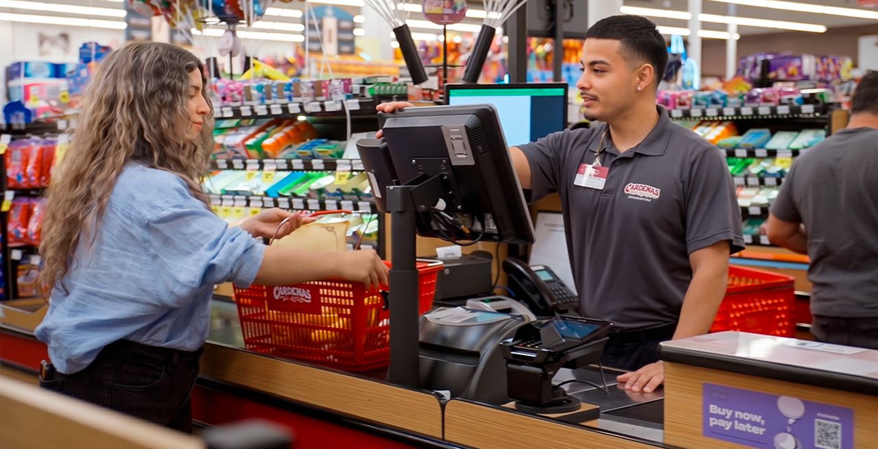 A clerk at Heritage Grocers assists a customer