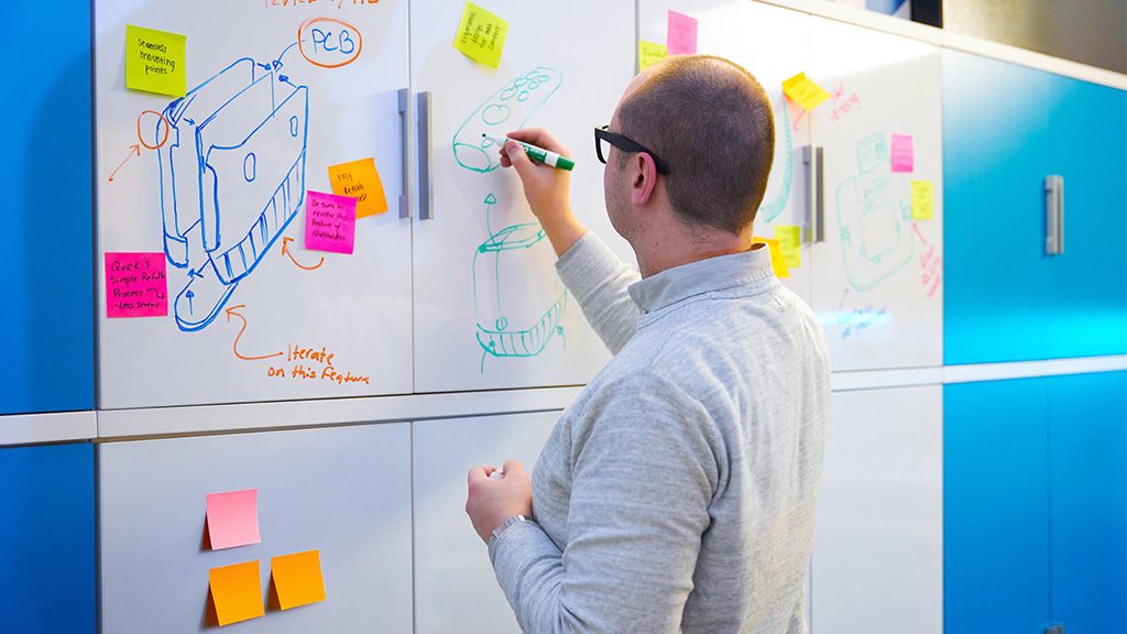 A Spectrum employee working out a problem on a dry erase board