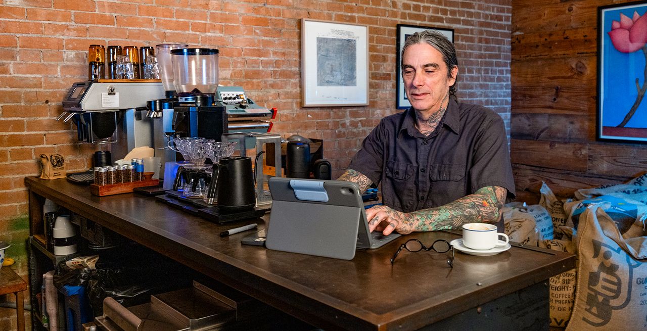 A coffee shop owner using a laptop in his store