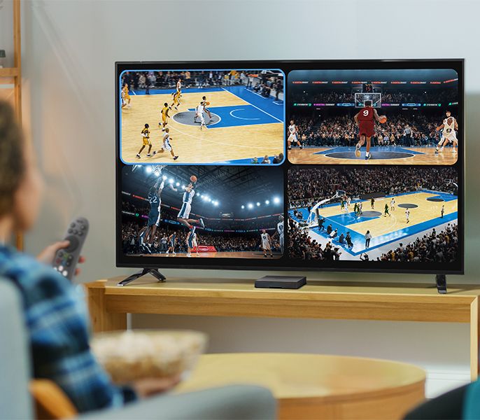 Family watching TV programming from their living room couch, viewed from behind