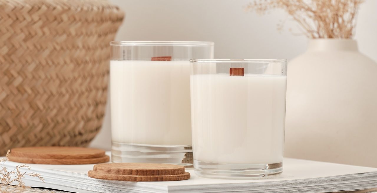 White candles with popsicle stick wicks sitting on a white table 