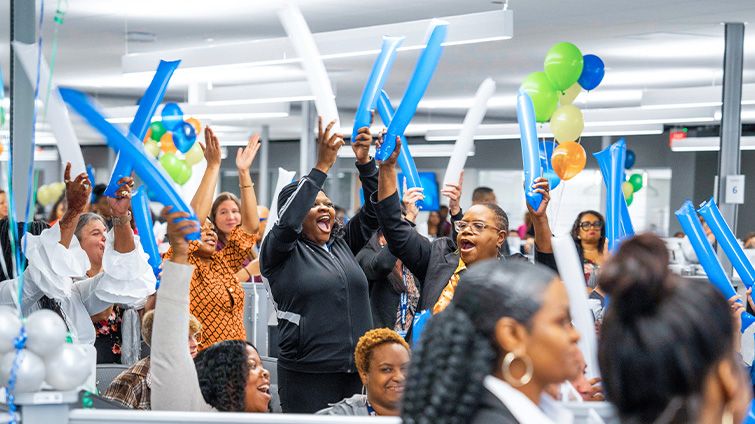 Spectrum employees celebrating during an an office event holding balloons over their heads