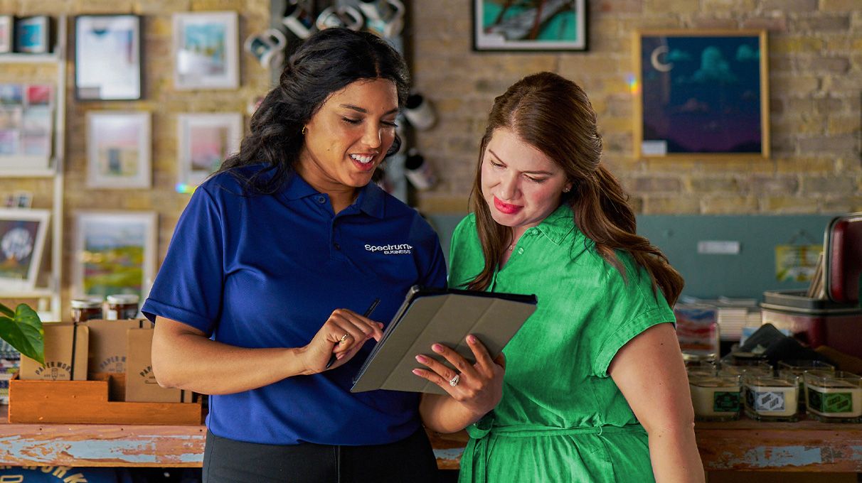 Two small business owners looking at a tablet together in their place of business