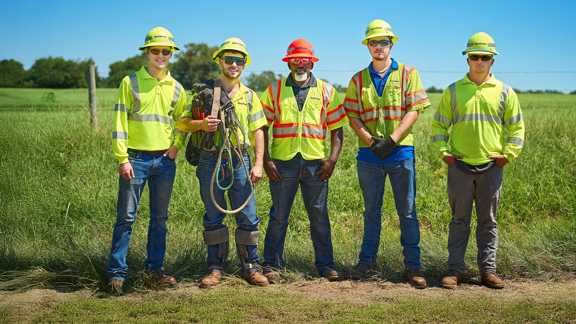 A group of five Spectrum field technicians posing in a row in a rural location