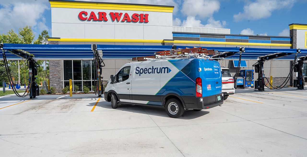 A Spectrum van parked in front of a car wash