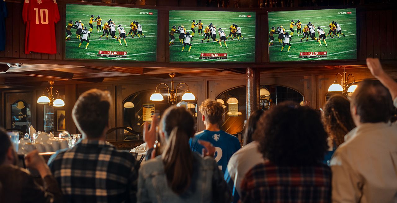 A group of people cheering at sports broadcasting at a bar