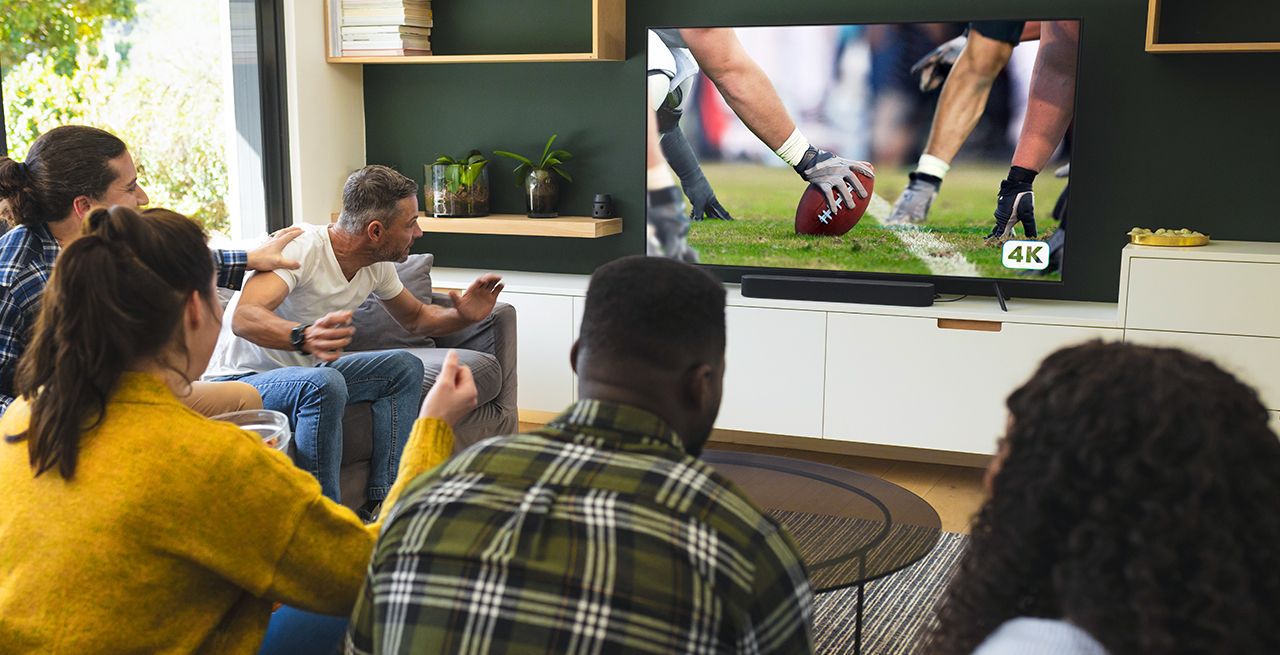 A group of people watching sports programming on a TV at home